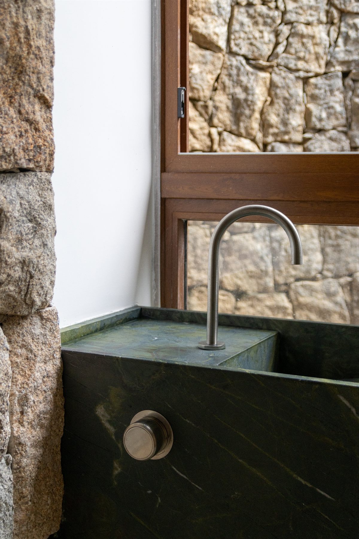 Lavabo em pedra verde com parede de pedra natural e caixilho de madeira